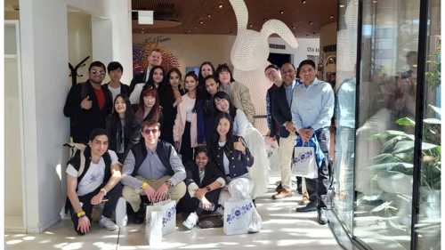 A group of Postgraduate students standing in a foyer posing and smiling towards the camera